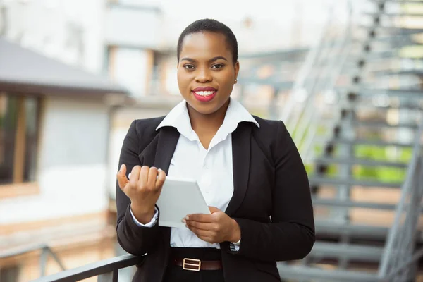 Afroamerikansk affärskvinna i kontorskläder ler, ser självsäker och glad, framgångsrik — Stockfoto