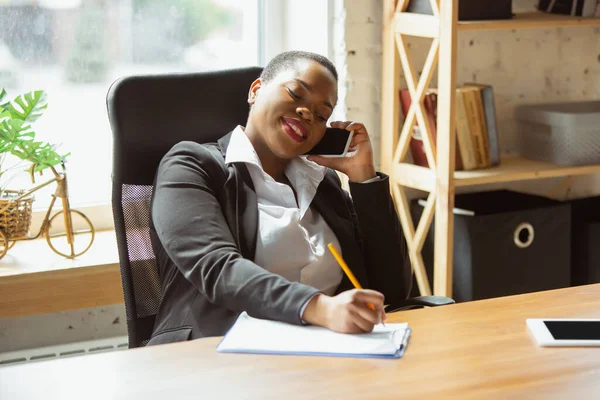 Mujer de negocios afroamericana en traje de oficina sonriendo, se ve confiada y feliz, exitosa —  Fotos de Stock