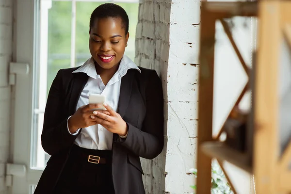African-american businesswoman in office attire smiling, looks confident and happy, successful — Stock Photo, Image