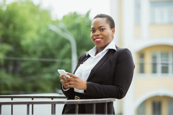 Donna d'affari afro-americana in abito da ufficio sorridente, sembra fiduciosa e felice, di successo — Foto Stock