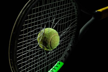 Siyah stüdyo arka planında izole edilmiş profesyonel spor ekipmanları. Tenis raketi ve top.
