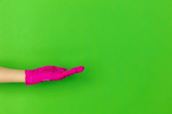 Рука в рожевій гумовій рукавичці, що показує, представлення ізольовано на зеленому студійному фоні з копійкою . — стокове фото