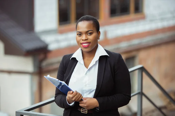 Empresária afro-americana em traje de escritório sorrindo, parece confiante e feliz, bem sucedida — Fotografia de Stock