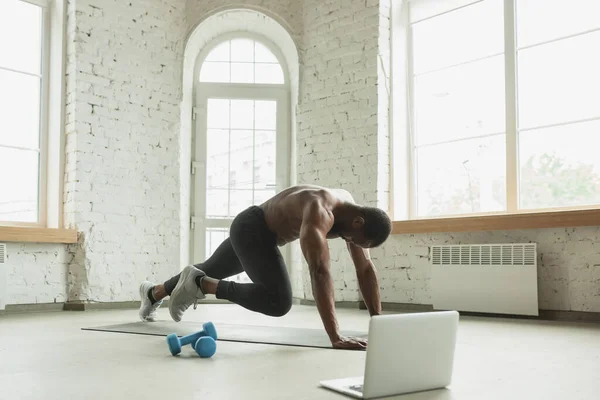 Mladý afroameričan trénuje doma během karantény vypuknutí koronaviru, doinkové cvičení fitness, aerobic. Pobyt sportovní zajištění izolace. — Stock fotografie