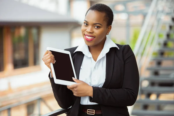 Mujer de negocios afroamericana en traje de oficina sonriendo, se ve confiada y feliz, exitosa —  Fotos de Stock