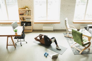 Koronavirüs salgını karantinası sırasında evde eğitim görmüş genç Afro-Amerikan erkek sporları, aerobik. Sportif kalıp izolasyon sağlıyorum..