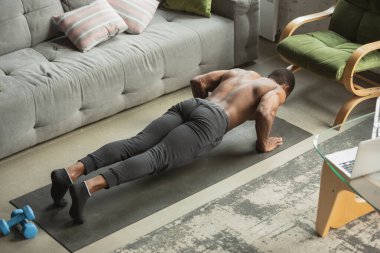 Koronavirüs salgını karantinası sırasında evde eğitim görmüş genç Afro-Amerikan erkek sporları, aerobik. Sportif kalıp izolasyon sağlıyorum..