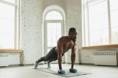 Koronavirüs salgını karantinası sırasında evde eğitim görmüş genç Afro-Amerikan erkek sporları, aerobik. Sportif kalıp izolasyon sağlıyorum..