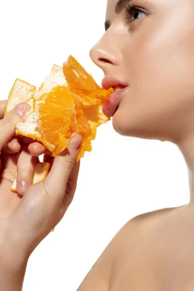 Energía. Primer plano de hermosa mujer joven mordiendo naranja jugosa sobre fondo blanco. Cosméticos y maquillaje, tratamiento natural y ecológico, cuidado de la piel . — Foto de Stock