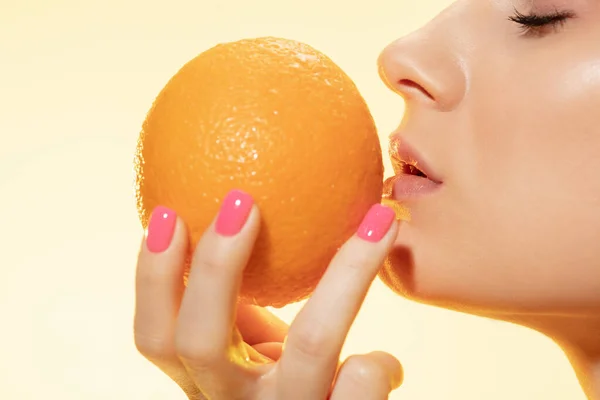 Close up de belo rosto feminino com laranja sobre fundo amarelo. Cosméticos e maquiagem, tratamento natural e ecológico, cuidados com a pele . — Fotografia de Stock