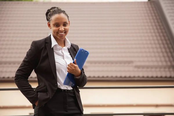 Mujer de negocios afroamericana en traje de oficina sonriendo, se ve confiada y feliz, exitosa —  Fotos de Stock