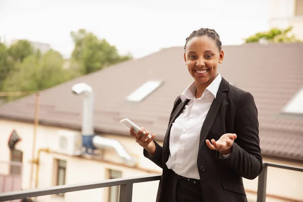 Mujer de negocios afroamericana en traje de oficina sonriendo, se ve confiada y feliz, exitosa —  Fotos de Stock