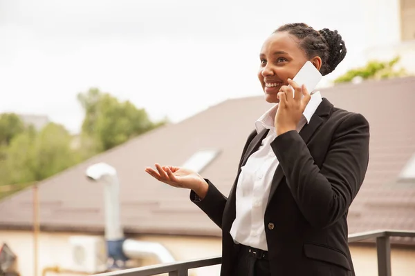 Mujer de negocios afroamericana en traje de oficina sonriendo, se ve confiada y feliz, exitosa —  Fotos de Stock