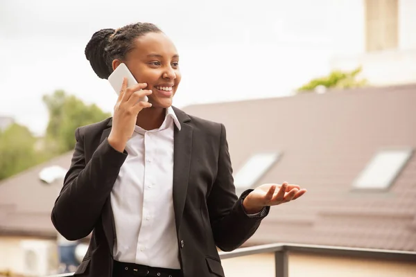 Mujer de negocios afroamericana en traje de oficina sonriendo, se ve confiada y feliz, exitosa —  Fotos de Stock