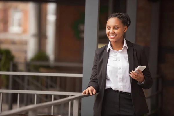 Mujer de negocios afroamericana en traje de oficina sonriendo, se ve confiada y feliz, exitosa —  Fotos de Stock