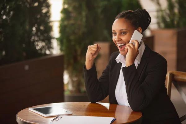 Mujer de negocios afroamericana en traje de oficina sonriendo, se ve confiada y feliz, exitosa —  Fotos de Stock