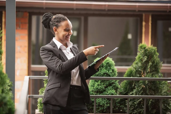 Mujer de negocios afroamericana en traje de oficina sonriendo, se ve confiada y feliz, exitosa —  Fotos de Stock