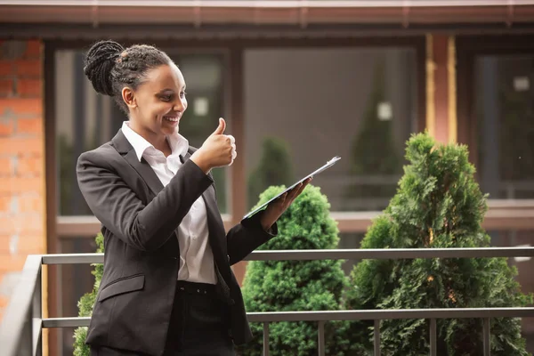 Mujer de negocios afroamericana en traje de oficina sonriendo, se ve confiada y feliz, exitosa —  Fotos de Stock