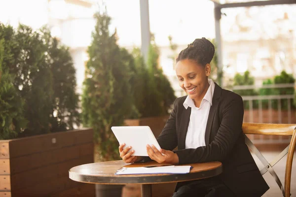 Mujer de negocios afroamericana en traje de oficina sonriendo, se ve confiada y feliz, exitosa —  Fotos de Stock