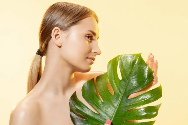 Een spa. Close-up van mooi vrouwelijk gezicht met groene bladeren over witte achtergrond. Cosmetica en make-up, natuurlijke en eco-behandeling, huidverzorging. — Stockfoto