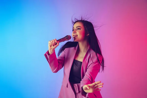 Kaukasische zangeres portret geïsoleerd op gradiënt studio achtergrond in neon licht — Stockfoto