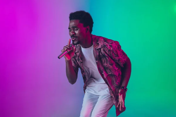 Afrikai-amerikai férfi énekes portré elszigetelt gradiens stúdió háttér neon fény — Stock Fotó