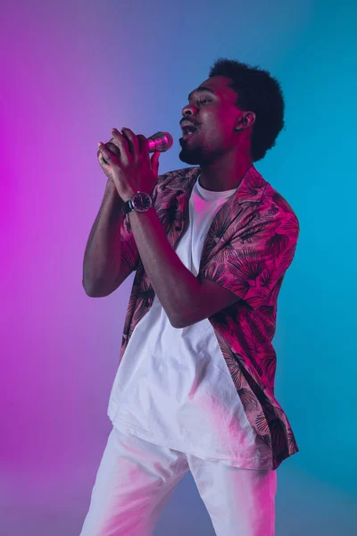 Retrato de cantor masculino afro-americano isolado no fundo do estúdio gradiente em luz de néon — Fotografia de Stock