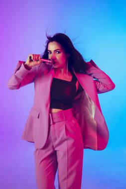 Beyaz kadın şarkıcı portresi neon ışıklı arka planda izole edilmiş.