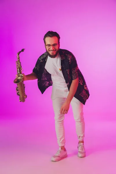 Młody biały muzyk jazzowy grający na saksofonie w neonowym świetle — Zdjęcie stockowe