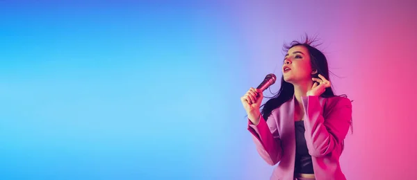 Retrato feminino cantor caucasiano isolado no fundo do estúdio gradiente em luz de néon, panfleto com copyspace para anúncio — Fotografia de Stock