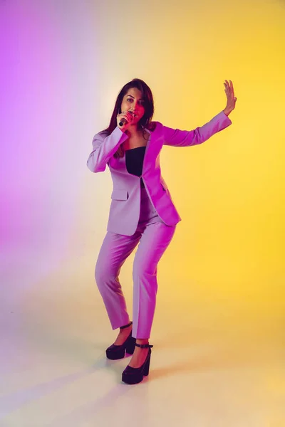 Kaukasische zangeres portret geïsoleerd op gradiënt studio achtergrond in neon licht — Stockfoto