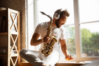 Beyaz müzisyen evdeki online konser sırasında saksafon çalıyor. Karantinaya alınmış, etkileyici bir doğaçlama.