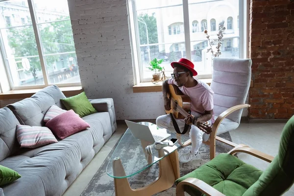 Músico afro-americano tocando guitarra durante concerto online em casa isolado e em quarentena, improvisação impressionante — Fotografia de Stock