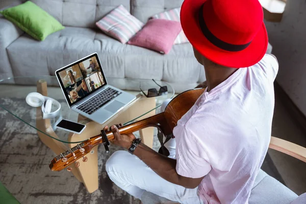 Músico afro-americano tocando guitarra durante concerto em casa isolado e em quarentena, improvisando impressionante com banda conectada online — Fotografia de Stock