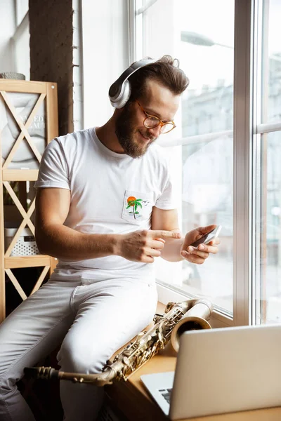 Kaukasischer Musiker bereitet sich zu Hause isoliert und unter Quarantäne auf ein Konzert vor, improvisiert eindrucksvoll mit online angeschlossener Band — Stockfoto