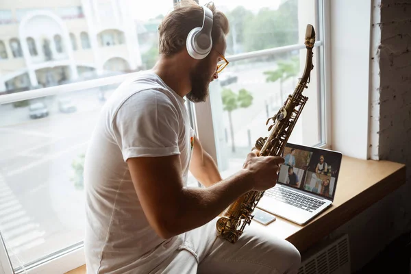 Кавказский музыкант играет на саксофоне во время онлайн-концерта дома изолированный и карантин, впечатляющая импровизация — стоковое фото