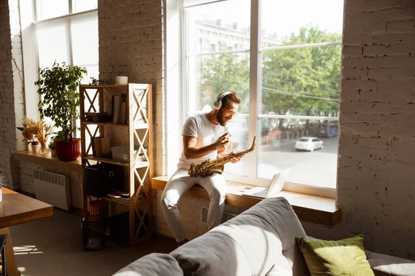 Caucasian musician playing saxophone during online concert at home isolated and quarantined, impressive improvising — Stock Photo, Image