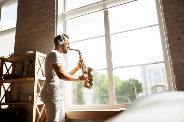 Músico caucásico tocando saxofón durante concierto en línea en casa aislado y en cuarentena, improvisación impresionante — Foto de Stock