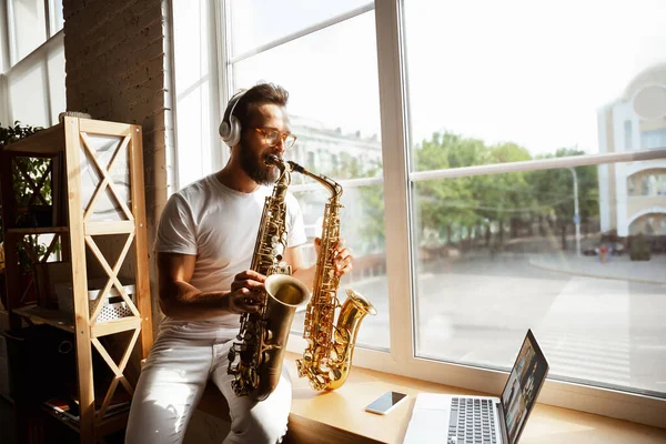 Kaukasische muzikant speelt saxofoon tijdens concert thuis geïsoleerd en in quarantaine, indrukwekkend improviseren met band online verbonden — Stockfoto
