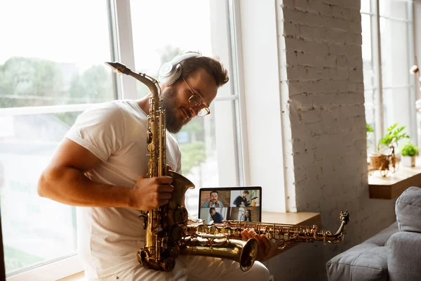 Músico caucásico preparándose para el concierto en casa aislado y en cuarentena, improvisación impresionante con banda conectada en línea — Foto de Stock