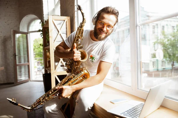 Músico caucásico eligiendo instrumento para concierto en casa aislado y en cuarentena, improvisación impresionante con banda conectada en línea —  Fotos de Stock