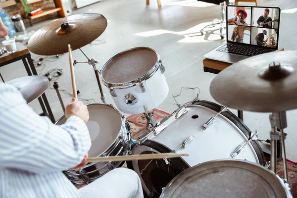 Primer plano de músico caucásico tocando tambores durante concierto en línea con la banda en casa aislado y atento, sonriente, alegre — Foto de Stock