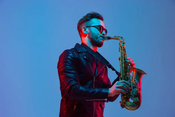 Joven músico de jazz caucásico tocando el saxofón con luz de neón — Foto de Stock