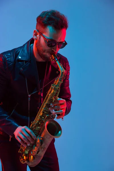 Giovane musicista jazz caucasico che suona il sassofono in luce al neon — Foto Stock