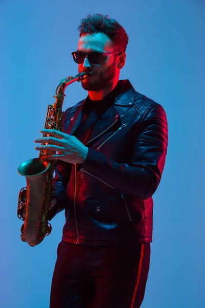 Joven músico de jazz caucásico tocando el saxofón con luz de neón — Foto de Stock