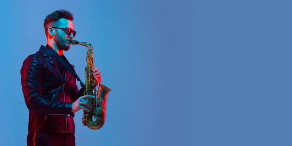 Joven músico de jazz caucásico tocando el saxofón con luz de neón, volante — Foto de Stock