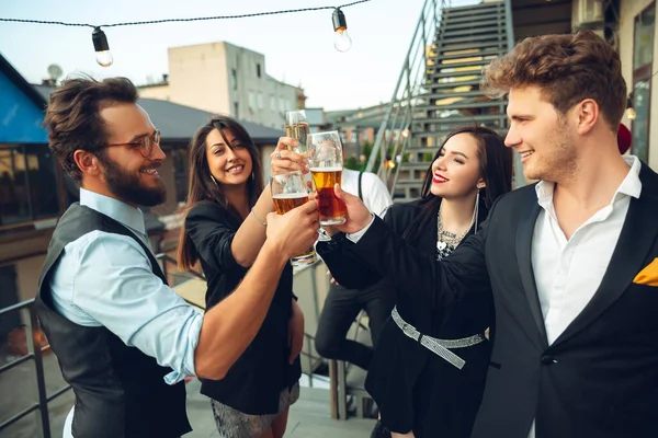 Grupo de jóvenes caucásicos celebrando, se ven felices, tienen fiesta corporativa en la oficina o bar — Foto de Stock