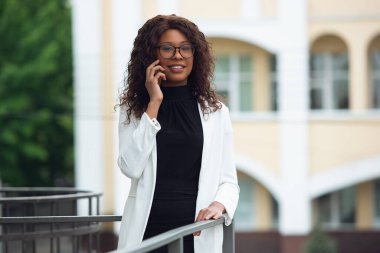 Güzel Afro-Amerikan iyi giyimli iş kadını kendinden emin, meşgul ve başarılı görünüyor.