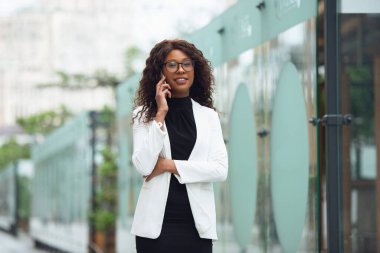 Güzel Afro-Amerikan iyi giyimli iş kadını kendinden emin, meşgul ve başarılı görünüyor.