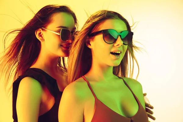 Nahaufnahme schöner Mädchen in modischen Badeanzügen und Brillen isoliert auf gelbem Studiohintergrund in Neonlicht. Sommer, Resort, Mode und Wochenendkonzept. — Stockfoto
